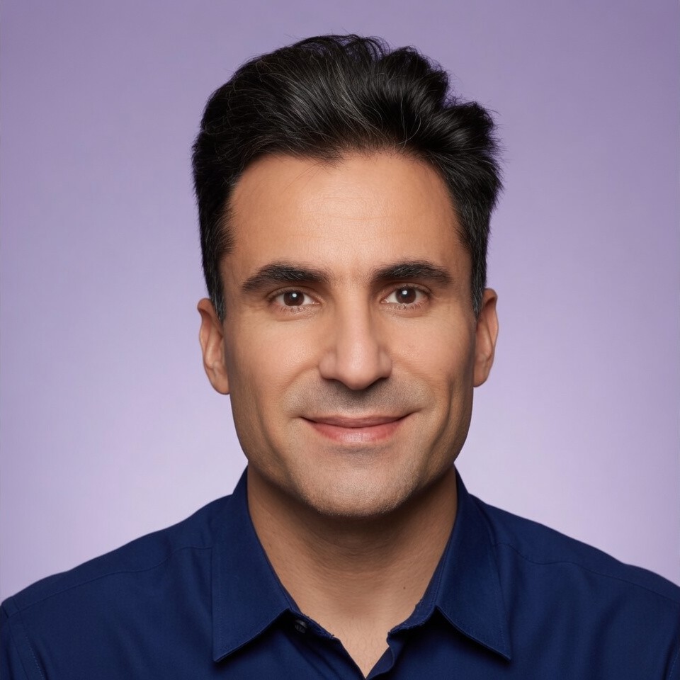Meet The Team 13 Mehdi Dana professional portrait with short dark hair, wearing dark blue collared shirt. Facing forward against smooth light purple gradient background with even lighting and clear focus, emphasising professionalism and clarity.